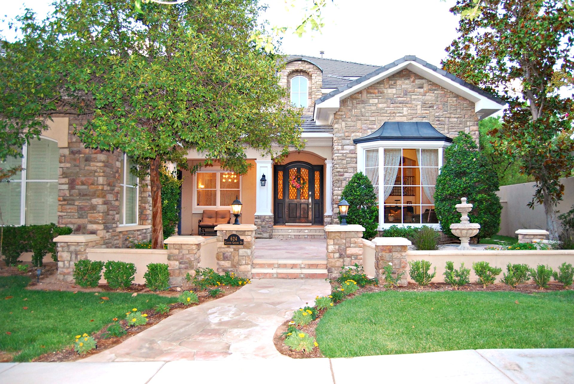 Front courtyard, stacked-stone pillars, and arched entry of 624 Canyon Greens at twilight